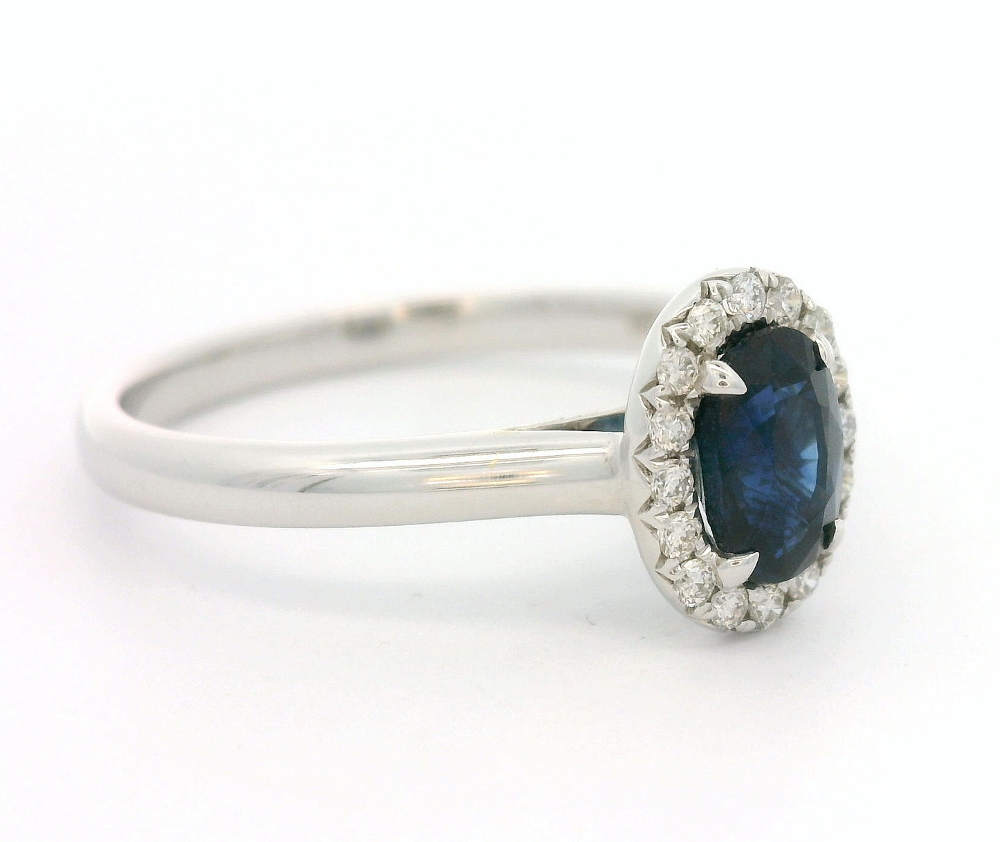 18 karaat witgouden Halo rozet ring van 2.74 gram. Bezet met 1 ovaal geslepen saffier van 0.80 crt en 16 briljant geslepen diamanten met een totaalgewicht van 0.12 crt. Kleur: G Kwaliteit: VS Zetting: 9 x 7 mm Model: R 10448
