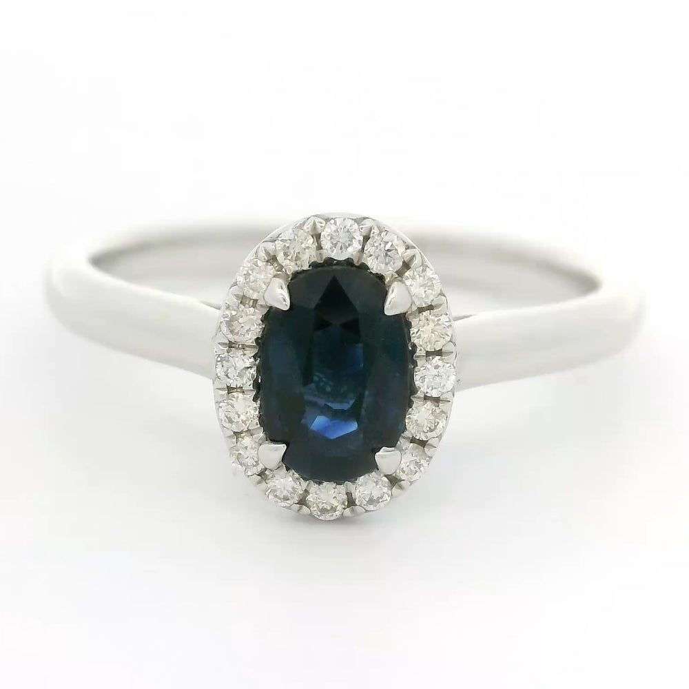 18 karaat witgouden Halo rozet ring van 2.74 gram. Bezet met 1 ovaal geslepen saffier van 0.80 crt en 16 briljant geslepen diamanten met een totaalgewicht van 0.12 crt. Kleur: G Kwaliteit: VS Zetting: 9 x 7 mm Model: R 10448
