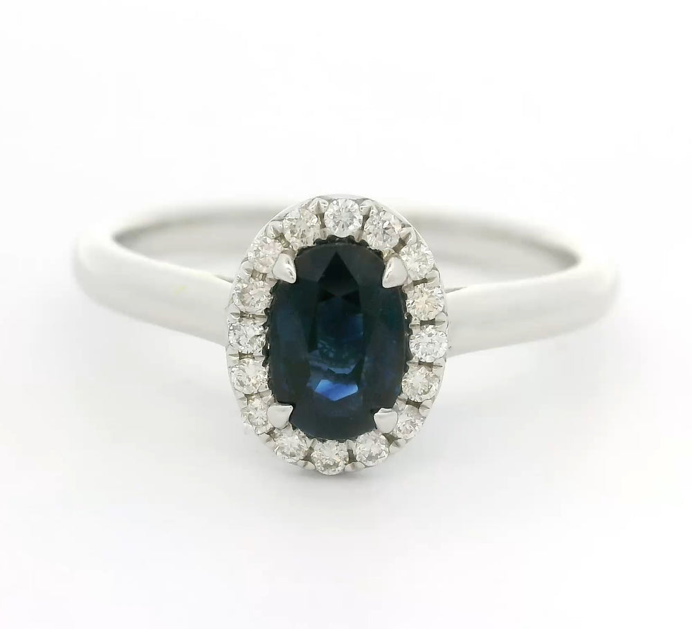 18 karaat witgouden Halo rozet ring van 2.74 gram. Bezet met 1 ovaal geslepen saffier van 0.80 crt en 16 briljant geslepen diamanten met een totaalgewicht van 0.12 crt. Kleur: G Kwaliteit: VS Zetting: 9 x 7 mm Model: R 10448
