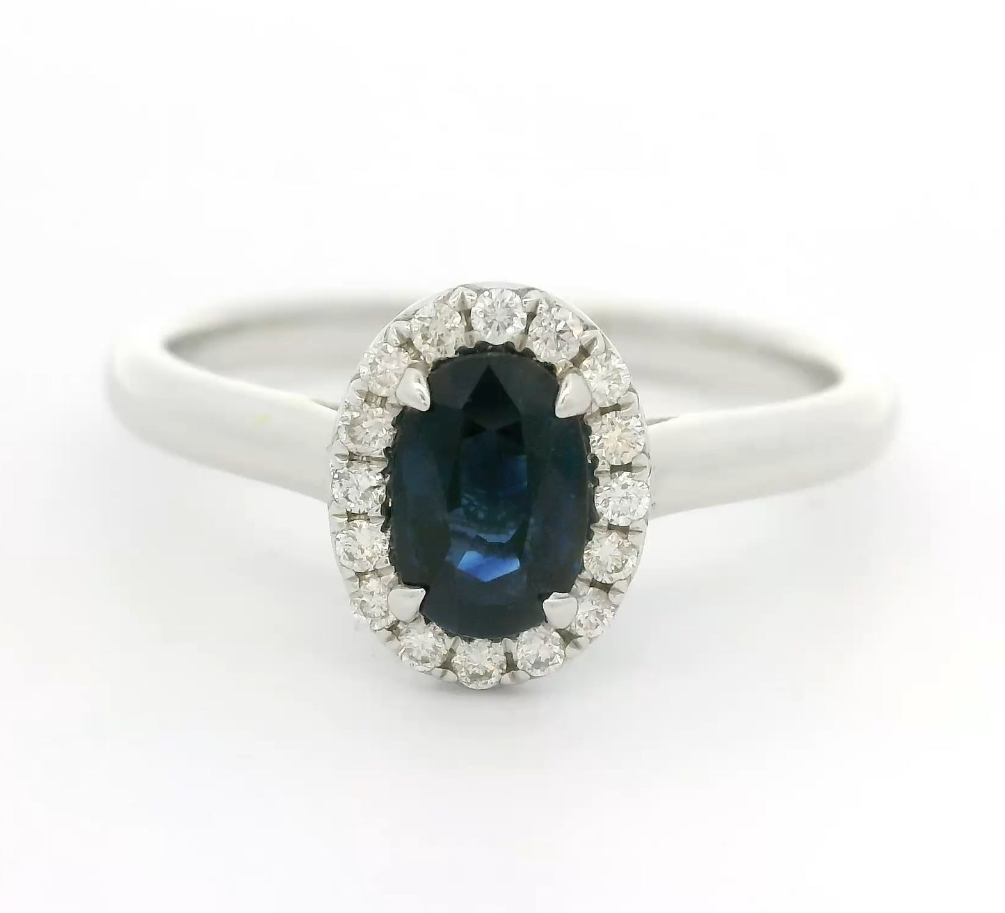 18 karaat witgouden Halo rozet ring van 2.74 gram. Bezet met 1 ovaal geslepen saffier van 0.80 crt en 16 briljant geslepen diamanten met een totaalgewicht van 0.12 crt. Kleur: G Kwaliteit: VS Zetting: 9 x 7 mm Model: R 10448
