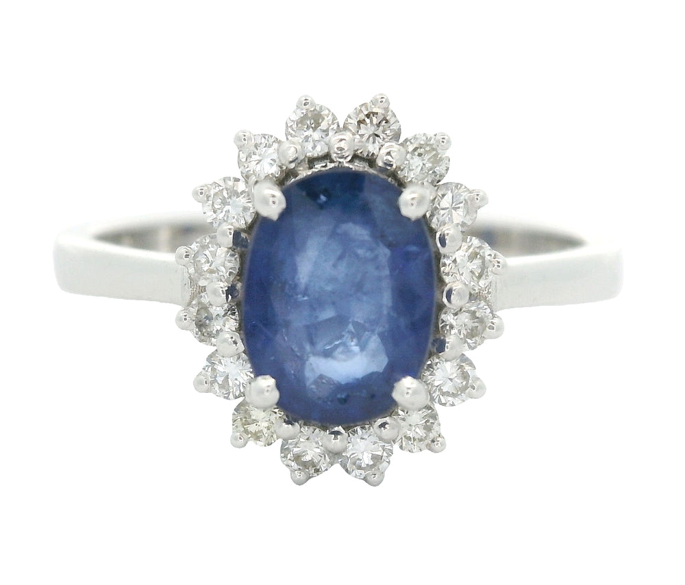 18 karaat witgouden rozetring van 3.3 gram. en 2.5 mm breed. Bezet met 1 ovaal geslepen saffier van 1.10 crt. en 16 briljant geslepen diamanten met een totaalgewicht van 0.16 crt. Kleur:G Kwaliteit: SI2 Zetting:11 x 9 mm Model: R 10543
