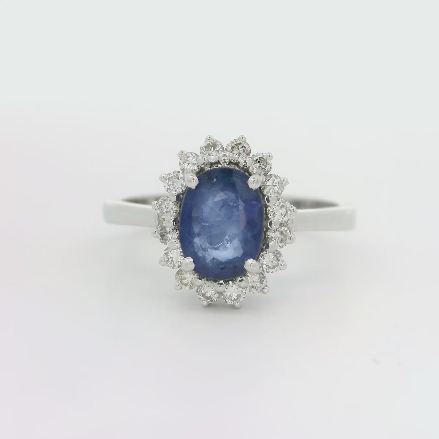 18 karaat witgouden rozetring van 3.3 gram. en 2.5 mm breed. Bezet met 1 ovaal geslepen saffier van 1.10 crt. en 16 briljant geslepen diamanten met een totaalgewicht van 0.16 crt. Kleur:G Kwaliteit: SI2 Zetting:11 x 9 mm Model: R 10543