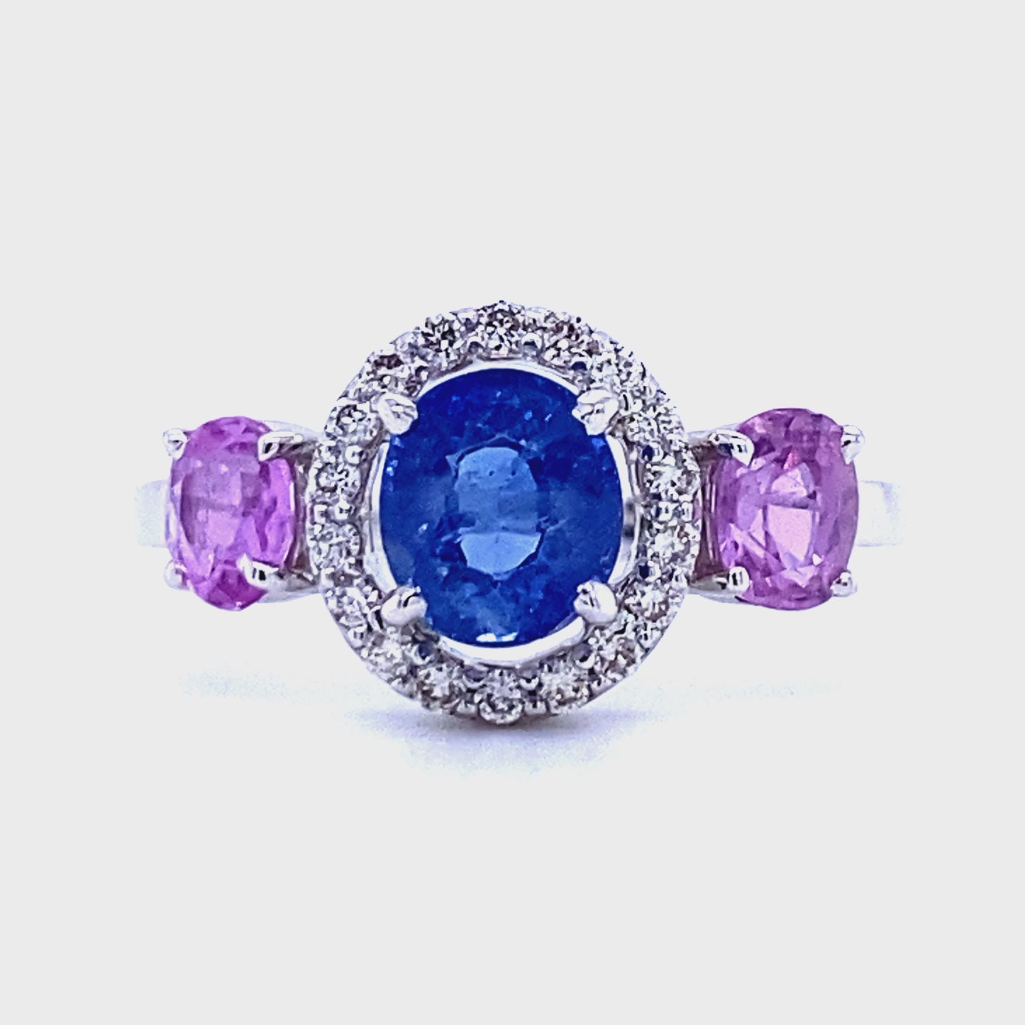 18 karaat wit gouden halo trilogie ring van 3.3 gram en 2 mm breed. Bezet met 18 briljant geslepen diamanten met een totaalgewicht van 0.20 crt. Kleur: Cape Kwaliteit: VS en 3 ovaal geslepen saffieren met een totaalgewicht van 2.26 crt Kleur: Blauw en Roze Zetting: 10 x 17 mm Model: R 9758ovaal geslepen saffier