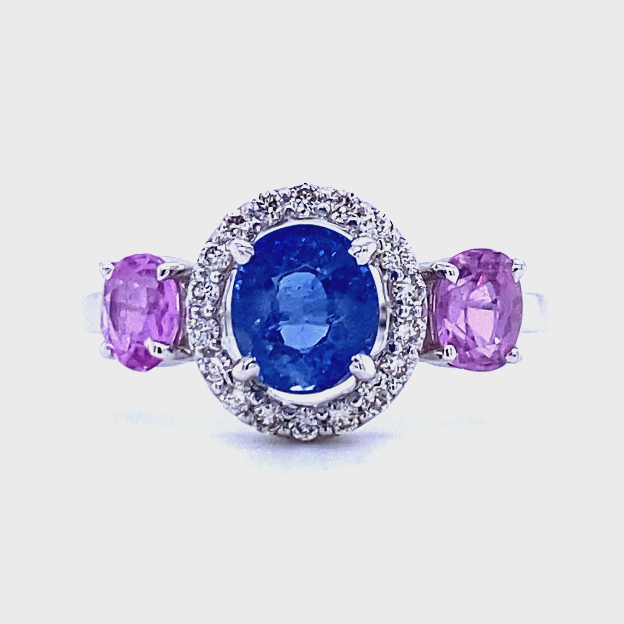 18 karaat wit gouden halo trilogie ring van 3.3 gram en 2 mm breed. Bezet met 18 briljant geslepen diamanten met een totaalgewicht van 0.20 crt. Kleur: Cape Kwaliteit: VS en 3 ovaal geslepen saffieren met een totaalgewicht van 2.26 crt Kleur: Blauw en Roze Zetting: 10 x 17 mm Model: R 9758ovaal geslepen saffier