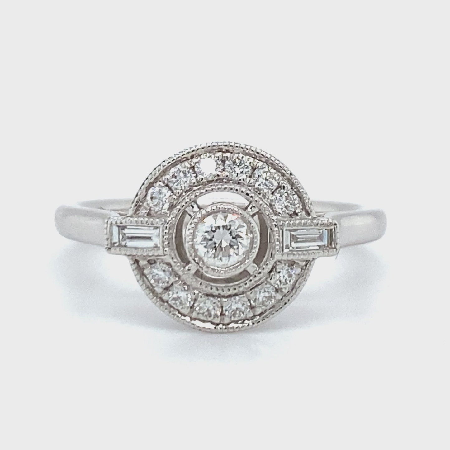 18 karaat Art Deco witgouden ring van 3.35 gram. Bezet met 13 briljant geslepen diamanten met een totaalgewicht van 0.26 crt en 2 baguette geslepen diamanten met een totaalgewicht van 0.10 crt Kleur: Top Wesselton Kwaliteit: VS Zetting: 11 x 13 mm Model R 9706