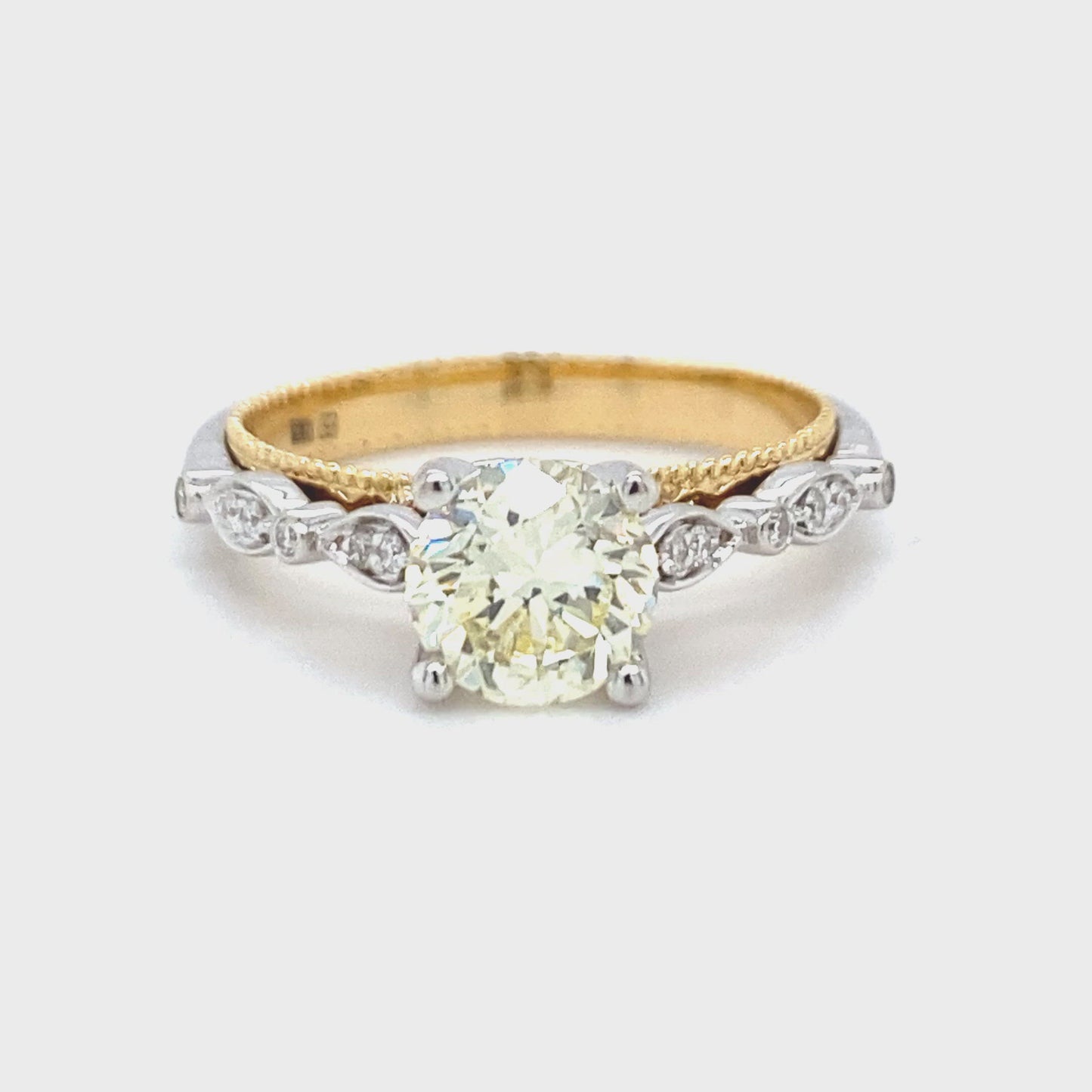 18 karaats wit met geel gouden fantasie ring van 4.15 gram en 3mm breed. Bezet met 1 briljant geslepen diamant van 1.12 crt kleur lichtgeel kwaliteit vs2 en 14 briljant geslepen diamanten met een totaalgewicht van 0.09 crt kleur G kwaliteit vs2 Model R8720