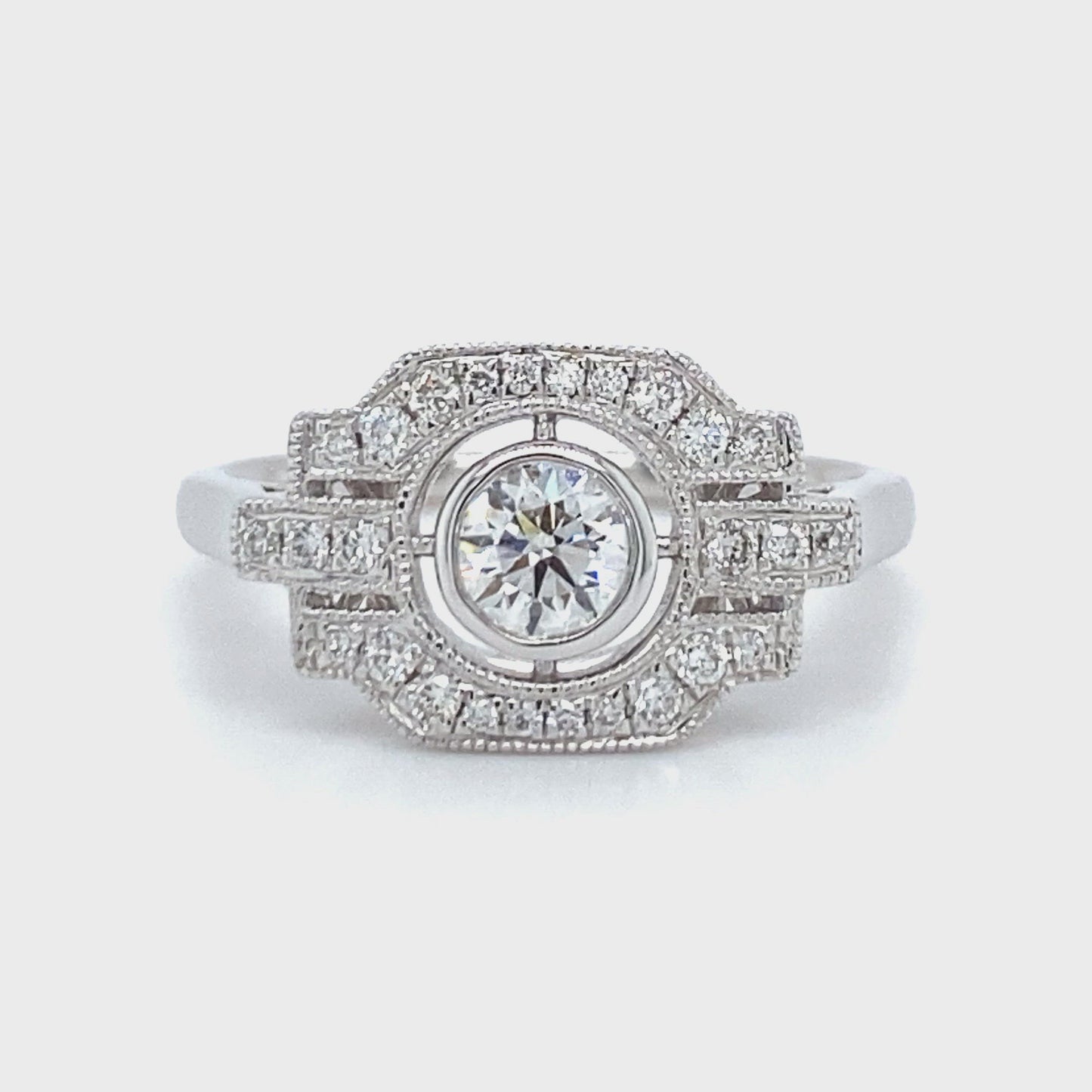 18 karaats witgouden Art Deco ring van 3.7 gram en 2 mm breed. Bezet met 1 briljant geslepen diamant van 0.17 crt en 27 briljant geslepen diamanten met een totaalgewicht van 0.27 crt Kleur: Top Wesselton Kwaliteit: VS Zetting: 10 x 16 mm Model R 9705