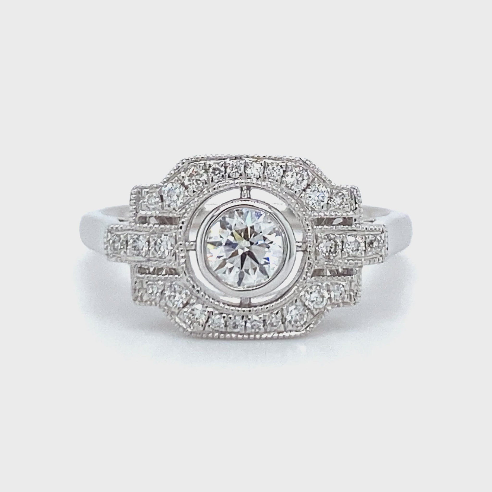 18 karaats witgouden Art Deco ring van 3.7 gram en 2 mm breed. Bezet met 1 briljant geslepen diamant van 0.17 crt en 27 briljant geslepen diamanten met een totaalgewicht van 0.27 crt Kleur: Top Wesselton Kwaliteit: VS Zetting: 10 x 16 mm Model R 9705