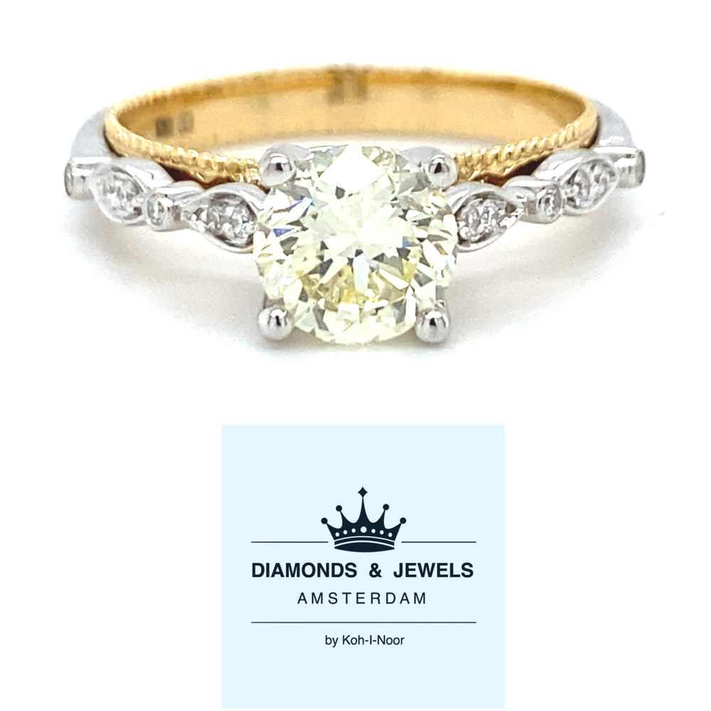 18 karaats wit met geel gouden fantasie ring van 4.15 gram en 3mm breed. Bezet met 1 briljant geslepen diamant van 1.12 crt kleur lichtgeel kwaliteit vs2 en 14 briljant geslepen diamanten met een totaalgewicht van 0.09 crt kleur G kwaliteit vs2 Model R8720