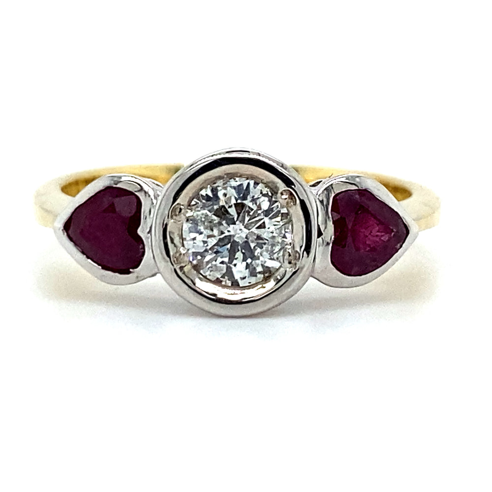 Geel gouden ring met een witgouden trilogie zetting. Bezet met 1 briljant geslepen diamant van 0.42 crt kleur top wesselton kwaliteit si3 en 2 hartvormig geslepen robijnen met een totaalgewicht van 0.65 crt Model R 3963