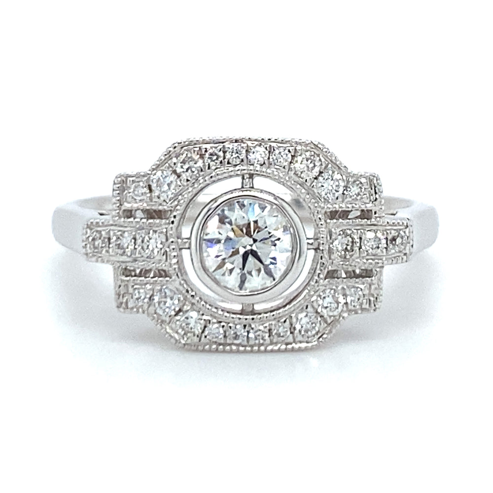 18 karaats witgouden Art Deco ring van 3.7 gram en 2 mm breed. Bezet met 1 briljant geslepen diamant van 0.17 crt en 27 briljant geslepen diamanten met een totaalgewicht van 0.27 crt Kleur: Top Wesselton Kwaliteit: VS Zetting: 10 x 16 mm Model R 9705