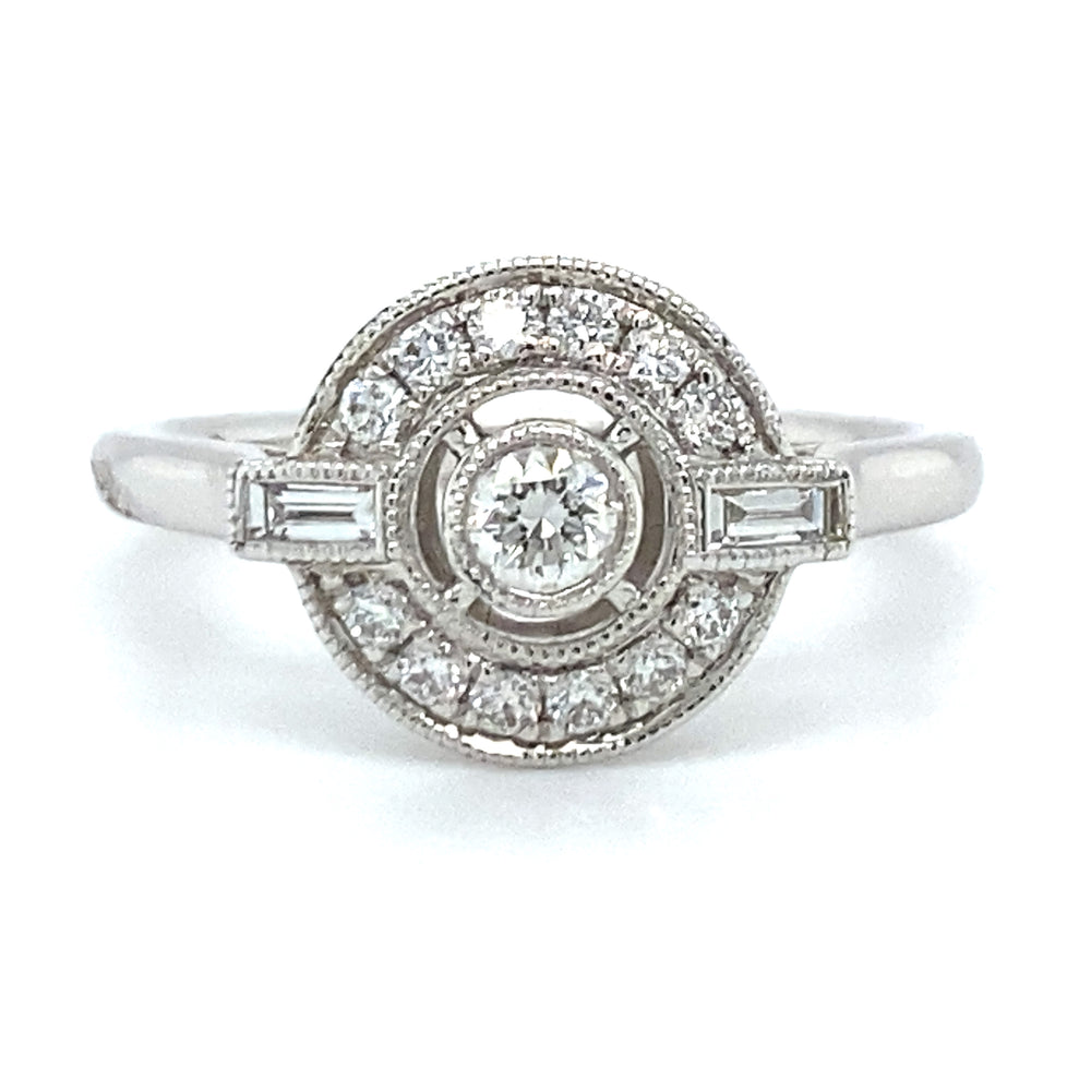 18 karaat Art Deco witgouden ring van 3.35 gram. Bezet met 13 briljant geslepen diamanten met een totaalgewicht van 0.26 crt en 2 baguette geslepen diamanten met een totaalgewicht van 0.10 crt Kleur: Top Wesselton Kwaliteit: VS Zetting: 11 x 13 mm Model R 9706