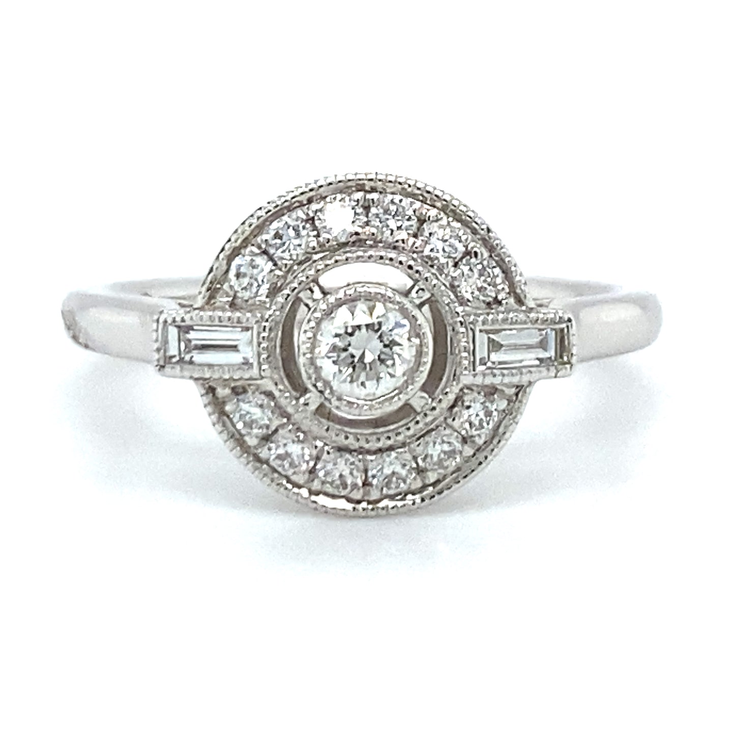 18 karaat Art Deco witgouden ring van 3.35 gram. Bezet met 13 briljant geslepen diamanten met een totaalgewicht van 0.26 crt en 2 baguette geslepen diamanten met een totaalgewicht van 0.10 crt Kleur: Top Wesselton Kwaliteit: VS Zetting: 11 x 13 mm Model R 9706